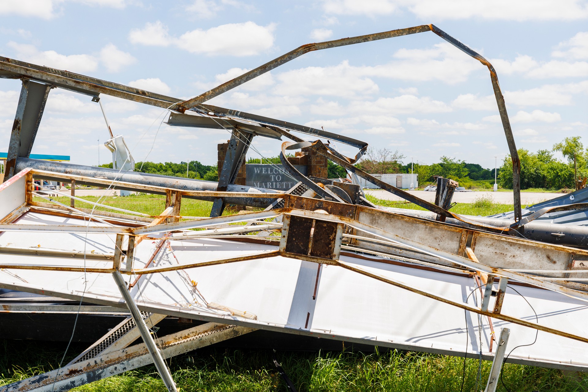 Welcome to Marietta. Twisted metal structures litter grassy field after severe weather event in Oklahoma outskirts